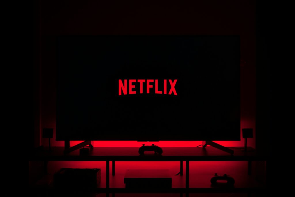 Television screen displaying Netflix logo in a dark room with red ambient lighting.
