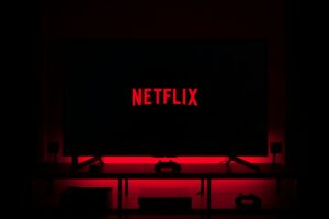 Television screen displaying Netflix logo in a dark room with red ambient lighting.